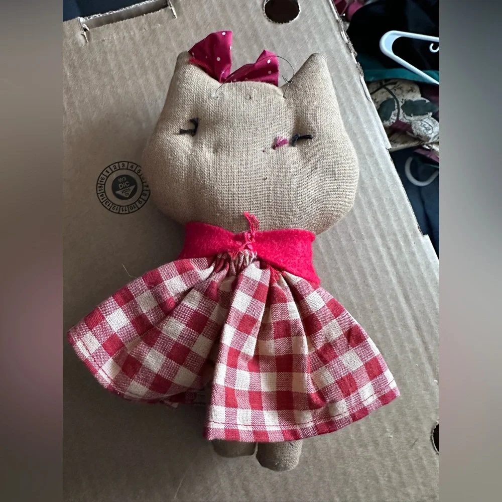 Handmade cloth cat doll in a red and white plaid dress.